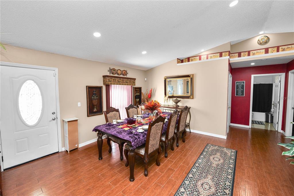 A dining room features a dark wood table, upholstered chairs, and hardwood flooring — 1127 PINECREST DRIVE, BARTOW, FL