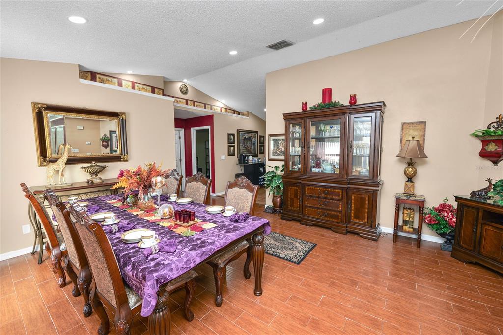 A dining room features a large wooden table with a purple tablecloth and a hutch — 1127 PINECREST DRIVE, BARTOW, FL