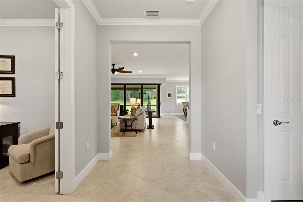 A tiled entryway leads through a wide archway into a living room with glass doors — 6839 CHESTER TRAIL, BRADENTON, FL