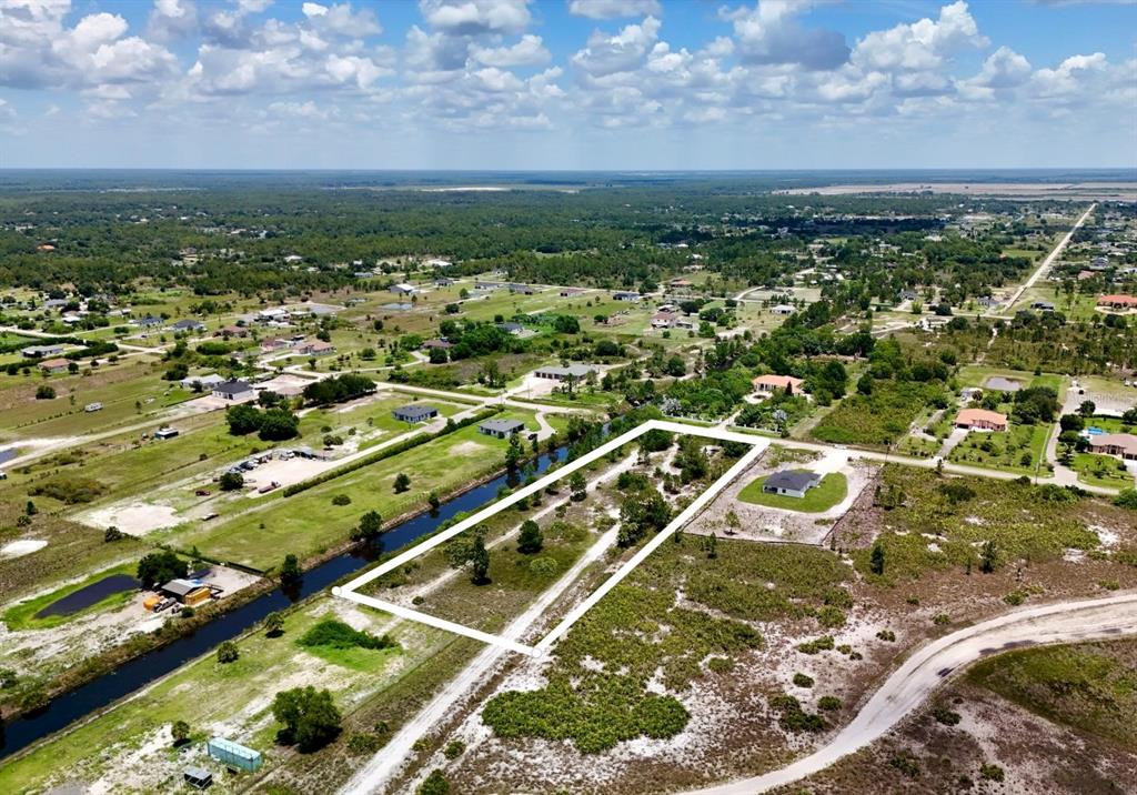 An aerial view shows a rectangular vacant lot outlined in white next to a canal — 0 60TH AVENUE NORTHEAST AVENUE NE, NAPLES, FL