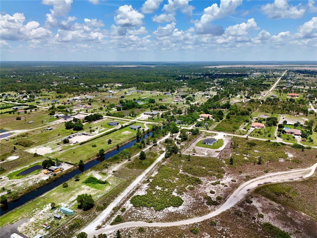 An aerial view shows a rural landscape with scattered houses, a canal, and dirt roads — 0 60TH AVENUE NORTHEAST AVENUE NE, NAPLES, FL