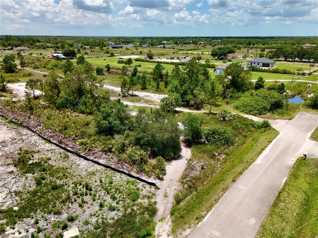 An aerial view shows a vacant, wooded lot next to a paved road — 0 60TH AVENUE NORTHEAST AVENUE NE, NAPLES, FL