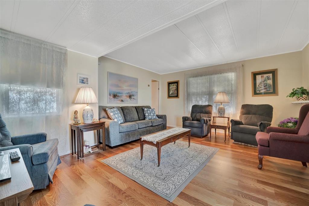 A living room with wood-look flooring, a gray sofa, several armchairs, and a coffee table — 128 E SAINT JOHNS WAY, APOLLO BEACH, FL