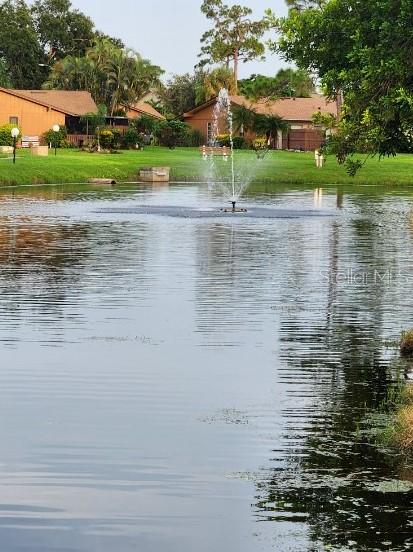 A fountain sprays water in the center of a pond surrounded by grass and houses — 5573 FOXLAKE DRIVE, NORTH FORT MYERS, FL