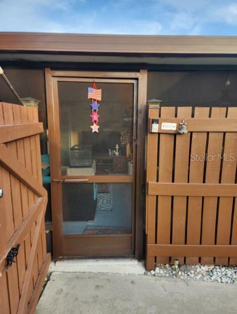 A brown screen door is centered between two wooden privacy fences on a concrete patio — 5573 FOXLAKE DRIVE, NORTH FORT MYERS, FL