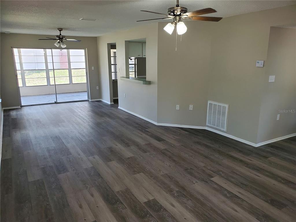 An open living room features wood-look flooring, a ceiling fan, and a pass-through kitchen window — 3936 SAILMAKER LANE, HOLIDAY, FL