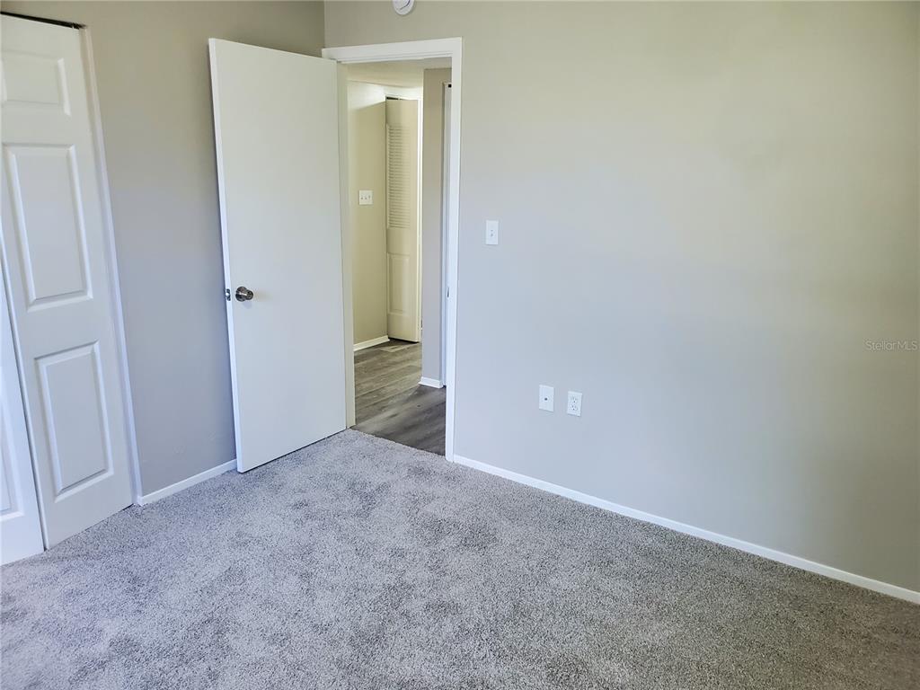 A bedroom with gray carpet, light-colored walls, and an open doorway leading to a hallway — 3936 SAILMAKER LANE, HOLIDAY, FL