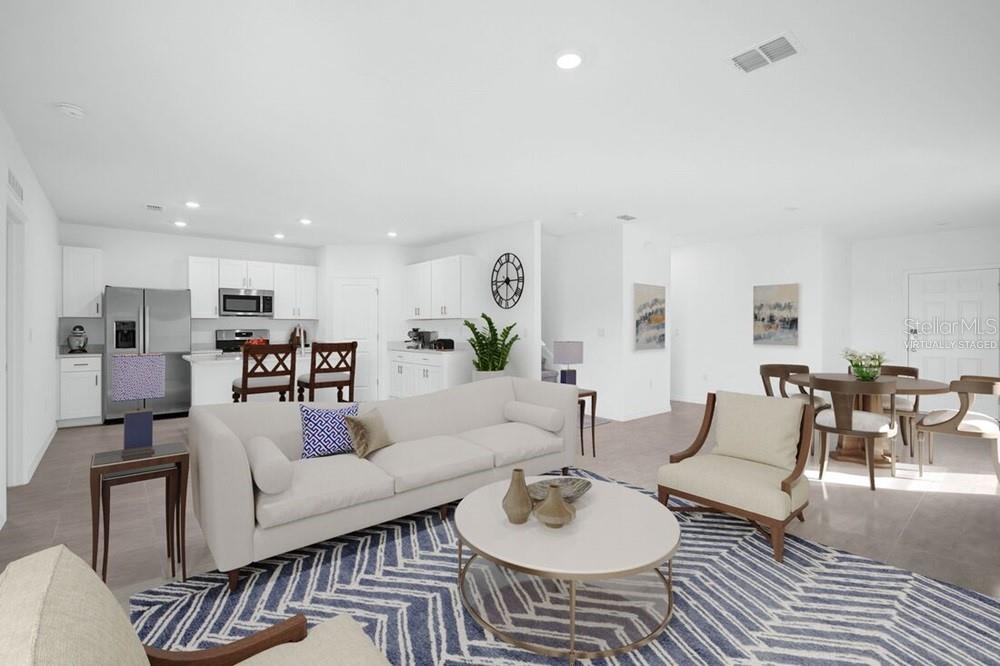 An open-concept living room and kitchen featuring white cabinetry, a sofa, and a dining area — 13835 SHELLMORE AVENUE, PALMETTO, FL