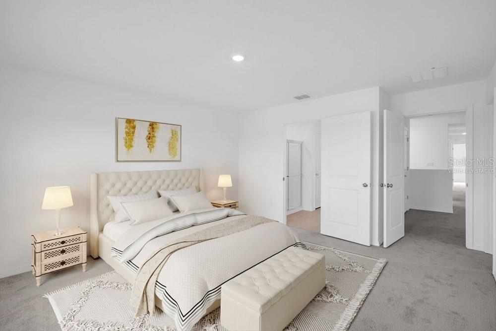 This virtually staged bedroom features a tufted headboard, neutral bedding, and gray carpeting — 13835 SHELLMORE AVENUE, PALMETTO, FL