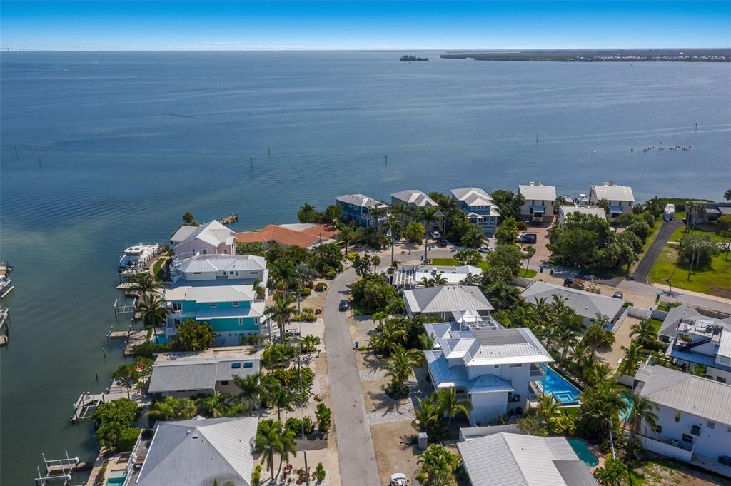 An aerial view shows waterfront homes along a coastal road with private docks and pools — 227 S HARBOR DRIVE, HOLMES BEACH, FL