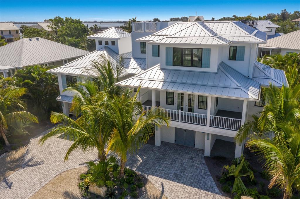 An elevated white coastal house with a metal roof and a paved driveway — 227 S HARBOR DRIVE, HOLMES BEACH, FL