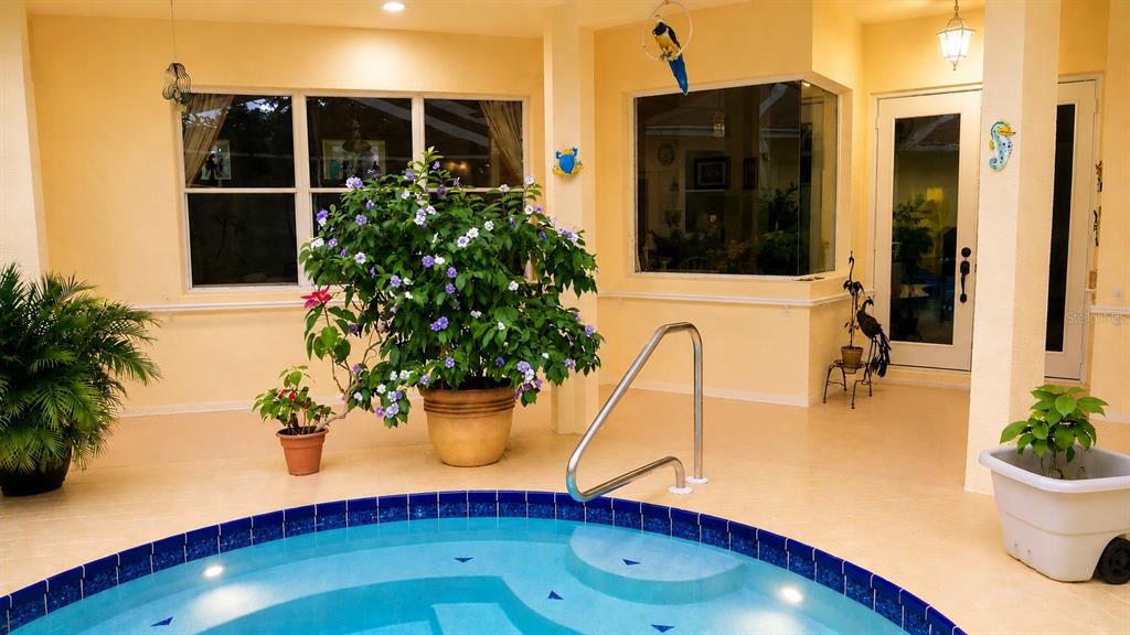 An indoor pool area features a circular tiled spa, potted plants, and large windows — 7517 JOMEL DRIVE, WEEKI WACHEE, FL