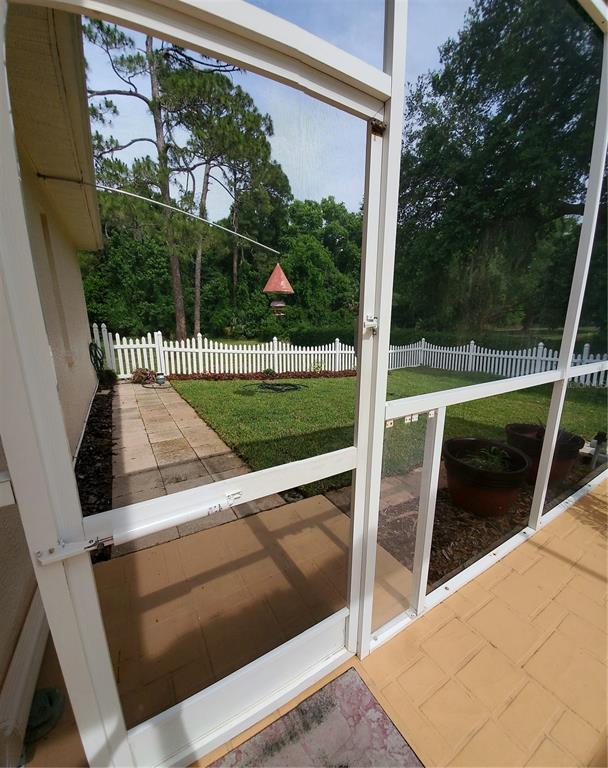 A view from a screened-in porch looking out onto a fenced backyard with a patio — 7517 JOMEL DRIVE, WEEKI WACHEE, FL