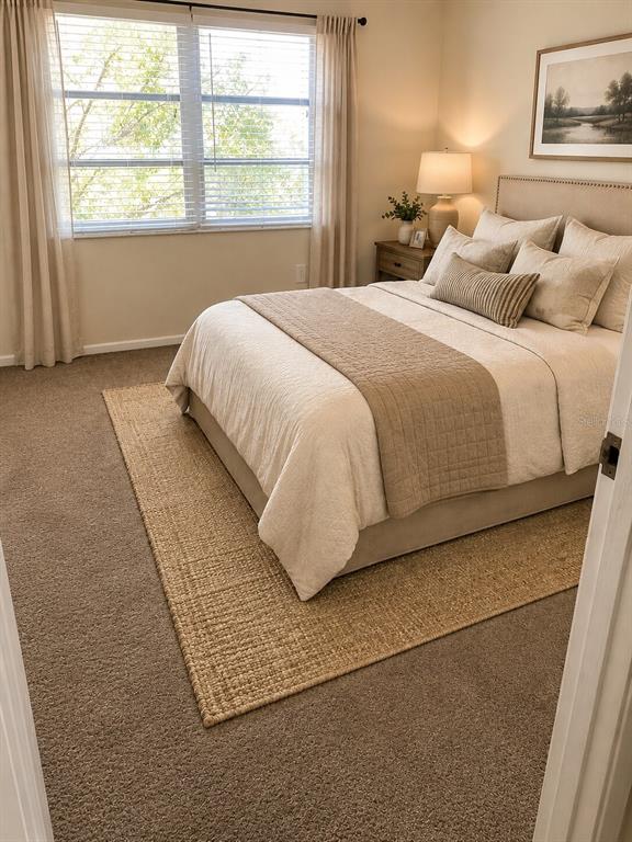 A bedroom features a bed with neutral bedding, a jute area rug, and a window — 247 S MCMULLEN BOOTH ROAD UNIT 24, CLEARWATER, FL
