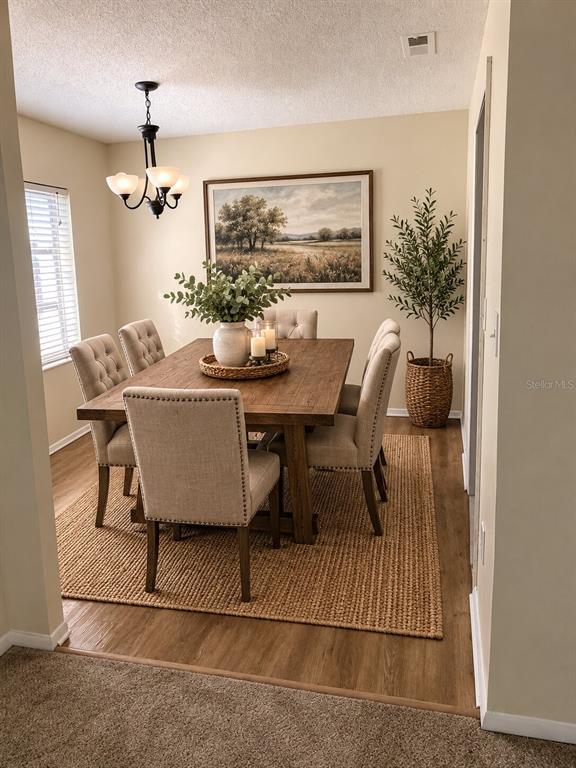 A dining room features a wooden table, upholstered chairs, a jute rug, and a landscape painting — 247 S MCMULLEN BOOTH ROAD UNIT 24, CLEARWATER, FL