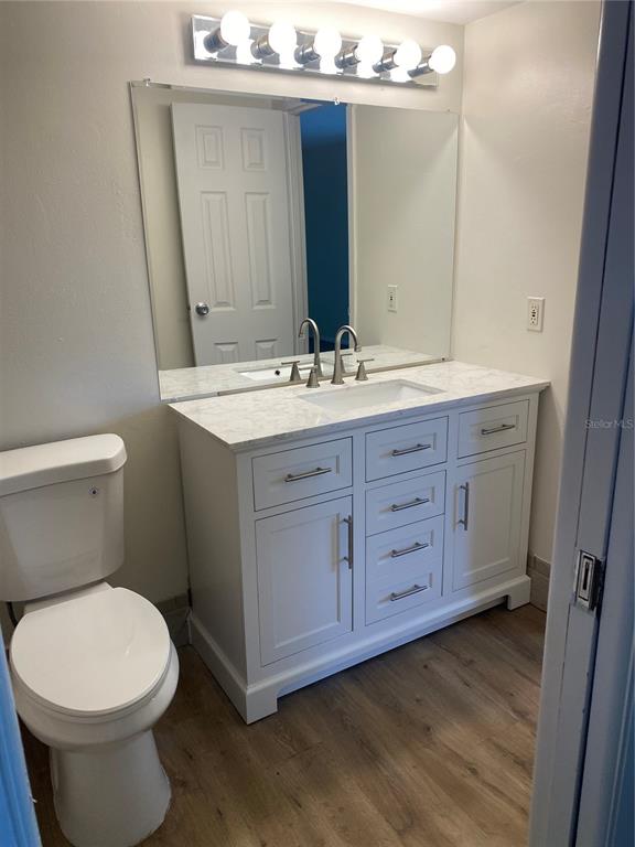 A bathroom features a white vanity with a marble countertop, a large mirror, and toilet — 247 S MCMULLEN BOOTH ROAD UNIT 24, CLEARWATER, FL