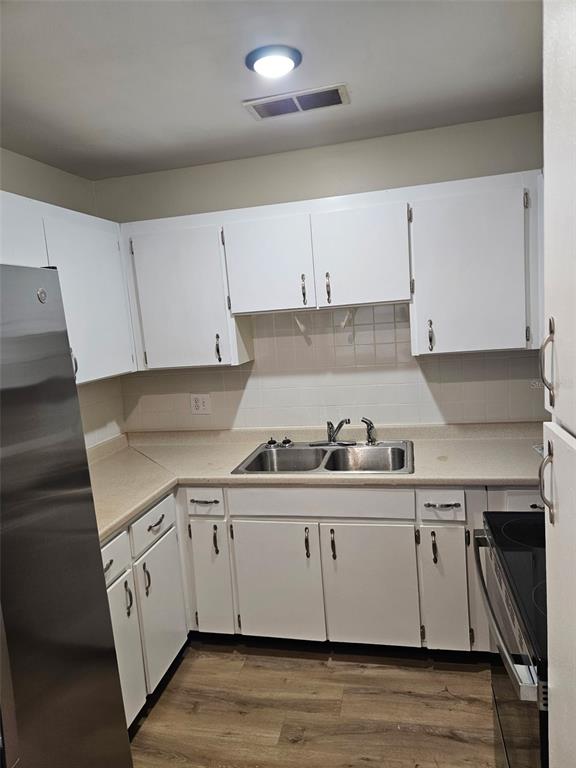 A kitchen features white cabinets, a stainless steel sink, and light-colored countertops — 247 S MCMULLEN BOOTH ROAD UNIT 24, CLEARWATER, FL