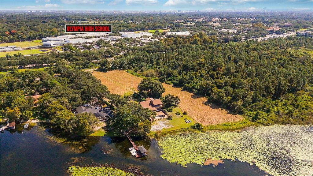 An aerial view shows two houses on a lakefront lot near a high school — 4226 DOWNEAST LANE, WINDERMERE, FL
