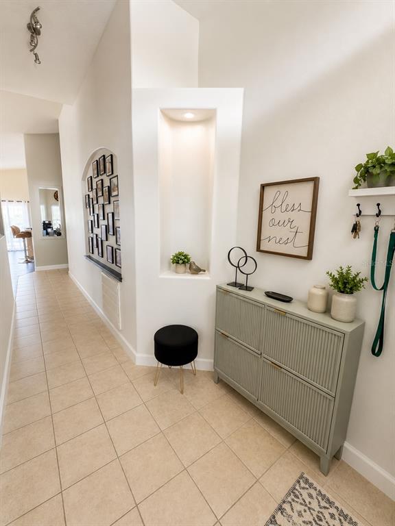 A hallway features a tiled floor, a built-in wall niche, and a sage green storage cabinet — 631 OLD BRIDGE CIRCLE, DAVENPORT, FL