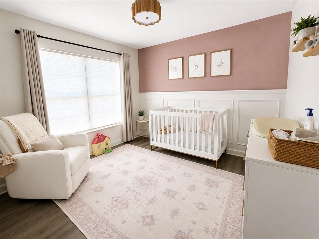 A nursery features a white crib, a cream armchair, and a pink accent wall with wainscoting — 631 OLD BRIDGE CIRCLE, DAVENPORT, FL