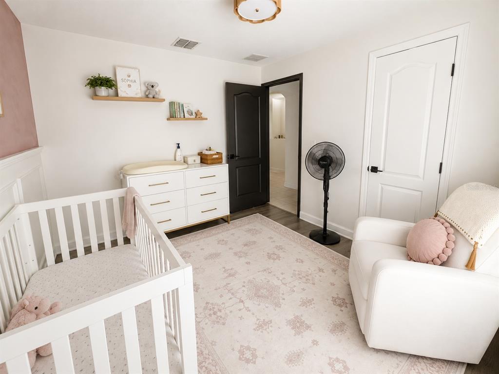 A nursery features a white crib, a changing dresser, a rocking chair, and a rug — 631 OLD BRIDGE CIRCLE, DAVENPORT, FL