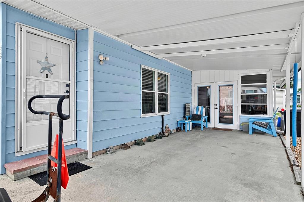 A light blue mobile home features a covered concrete carport and a white front door — 42 NAUTILUS DRIVE, FLAGLER BEACH, FL
