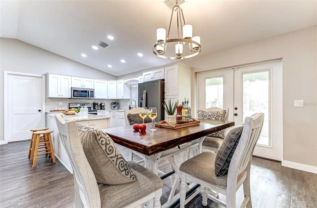 A dining area with a wooden table and chairs sits adjacent to a modern kitchen — 220 KITE AVENUE, SEBRING, FL