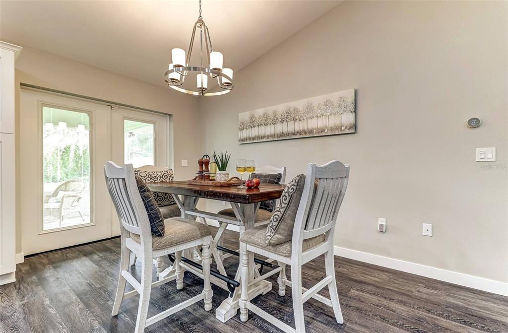 A dining area features a wooden table, four white chairs, and a modern chandelier — 220 KITE AVENUE, SEBRING, FL