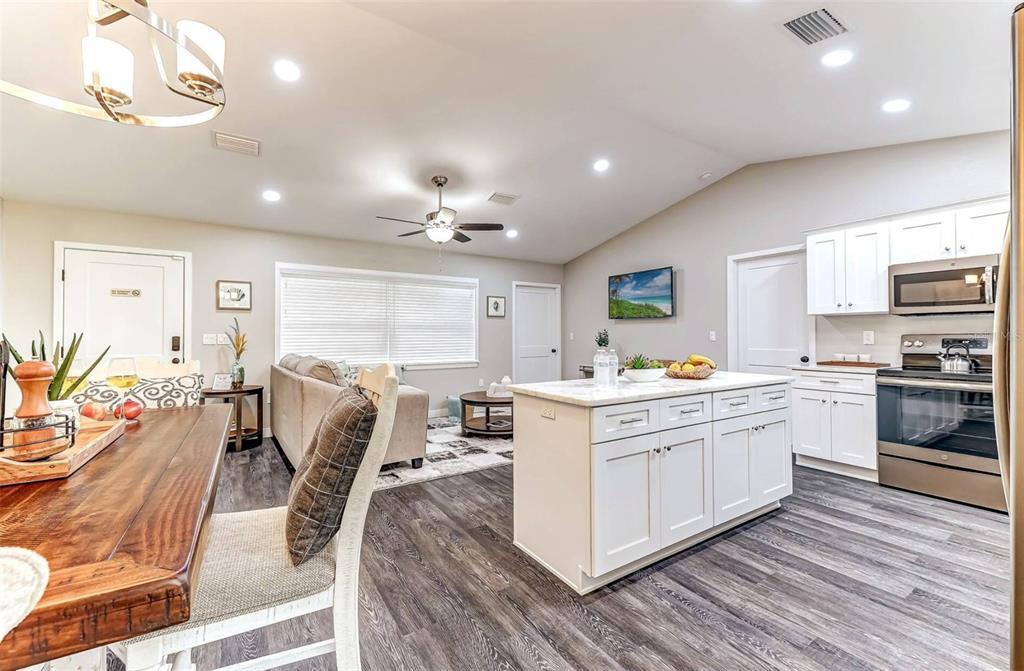 An open-concept kitchen and living area features white cabinetry, a kitchen island, and wood flooring — 220 KITE AVENUE, SEBRING, FL