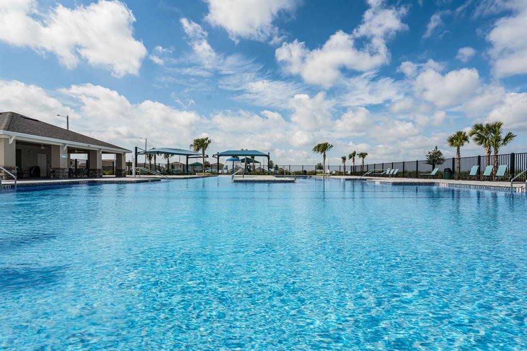 A large outdoor swimming pool with a covered patio area and palm trees under clouds — 2323 SELENIA STREET, LAKE ALFRED, FL