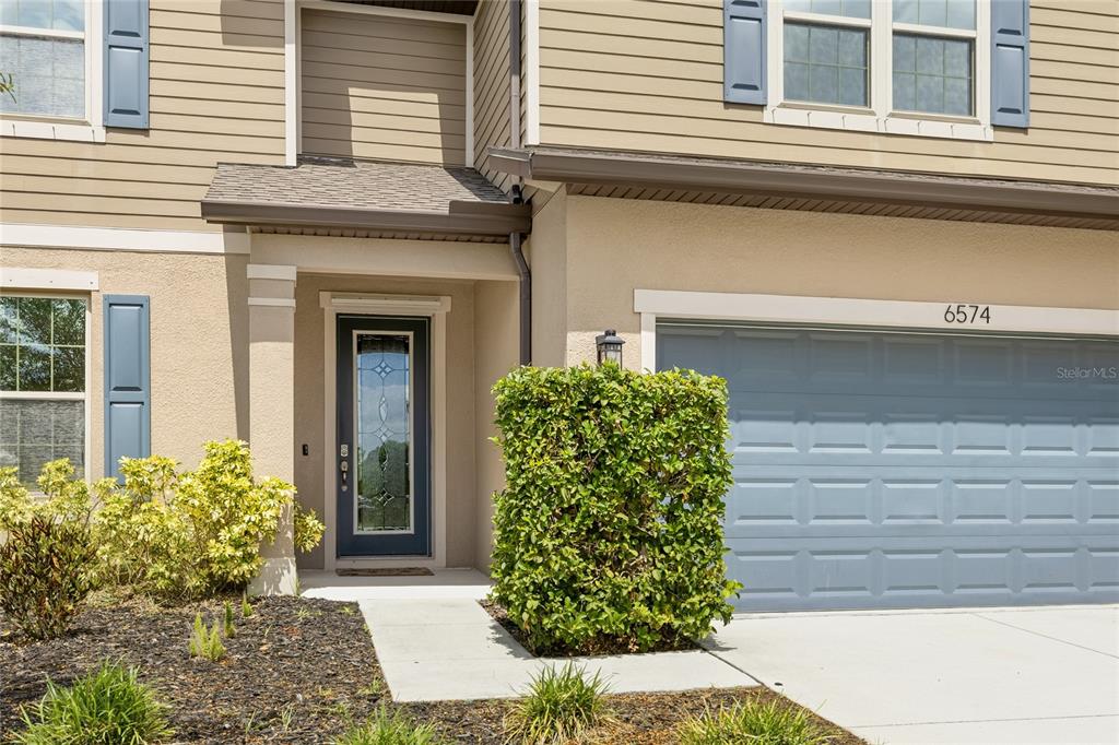 The exterior of a two-story house features a tan facade, blue shutters, and a garage — 6574 KENAVA LOOP, PALMETTO, FL