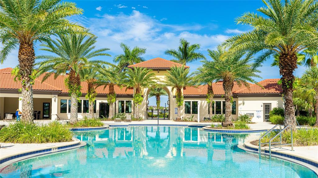 A swimming pool sits in front of a building with a tile roof and palm trees — 6574 KENAVA LOOP, PALMETTO, FL