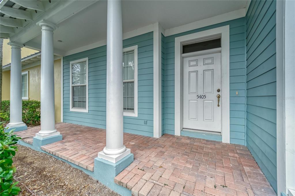 A front porch with brick pavers, white columns, and a blue-sided house exterior — 5405 CAFREY PLACE, APOLLO BEACH, FL