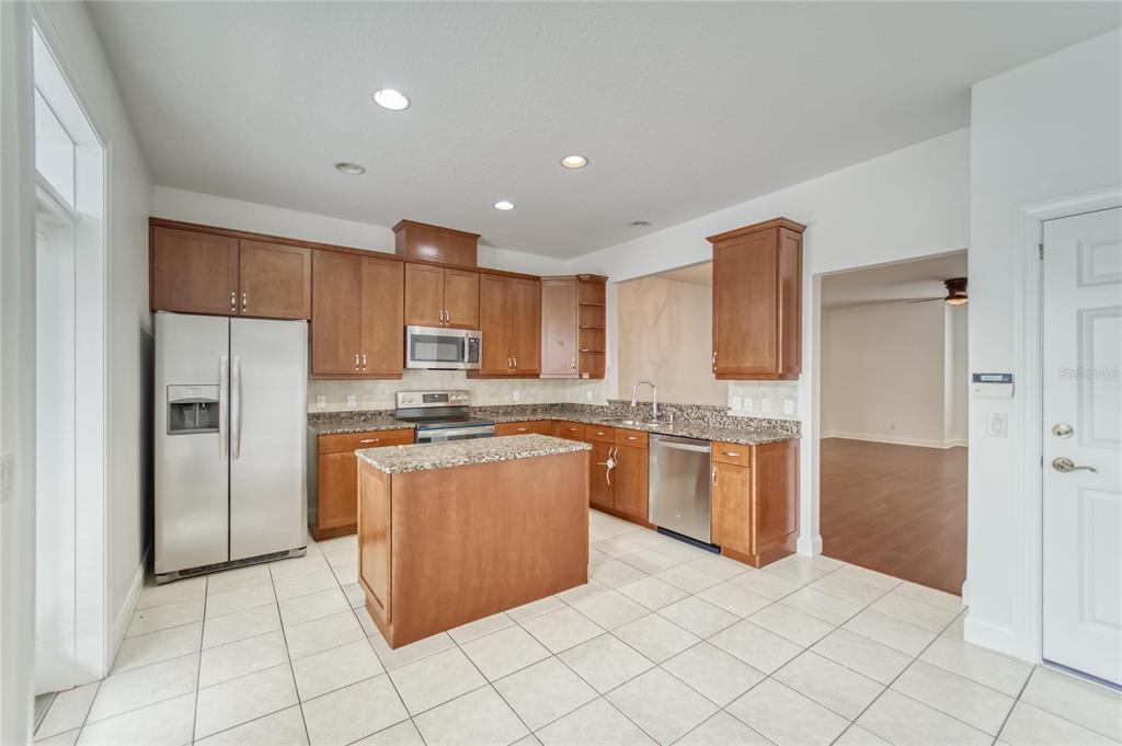 A kitchen with wood cabinets, granite countertops, stainless steel appliances, and a central island — 5405 CAFREY PLACE, APOLLO BEACH, FL