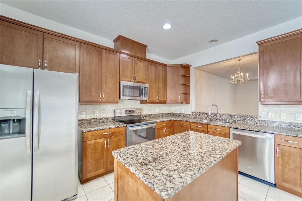 A kitchen with wood cabinets, granite countertops, stainless steel appliances, and a central island — 5405 CAFREY PLACE, APOLLO BEACH, FL