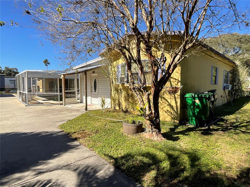 A yellow house with a screened-in pool enclosure and a concrete driveway — 700 JERSEY COURT, DUNDEE, FL
