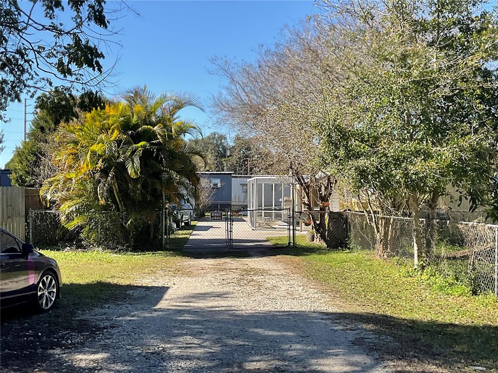 A gravel driveway leads to a fenced residential property with a mobile home and enclosure — 700 JERSEY COURT, DUNDEE, FL