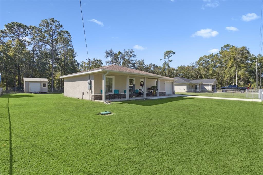 A single-story house with a covered porch, a shed, and a large grassy backyard — 61 GUAVA TRAIL, OCKLAWAHA, FL