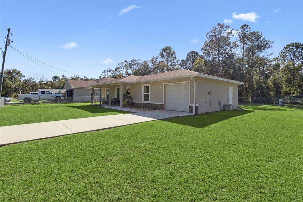 A single-story house with a beige exterior, a front porch, and an attached garage — 61 GUAVA TRAIL, OCKLAWAHA, FL