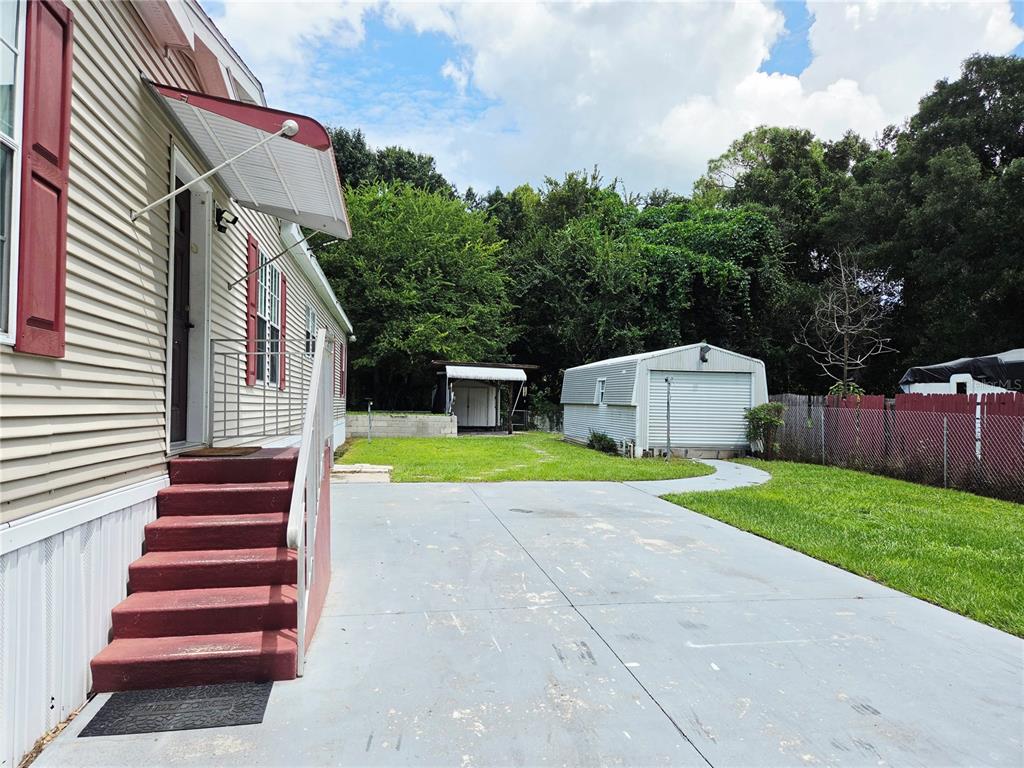 A concrete driveway leads to the side entrance of a house with red stairs — 6607 IVY MIST LANE, DAVENPORT, FL