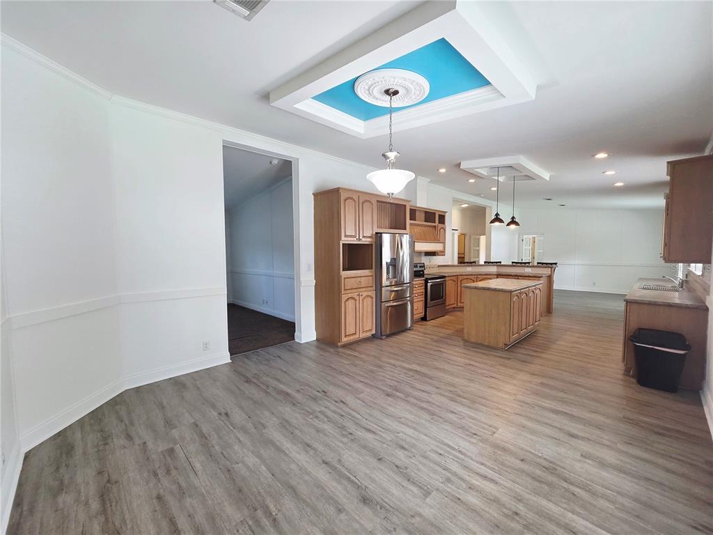 A kitchen with wood cabinets, a center island, and a blue tray ceiling with lighting — 6607 IVY MIST LANE, DAVENPORT, FL