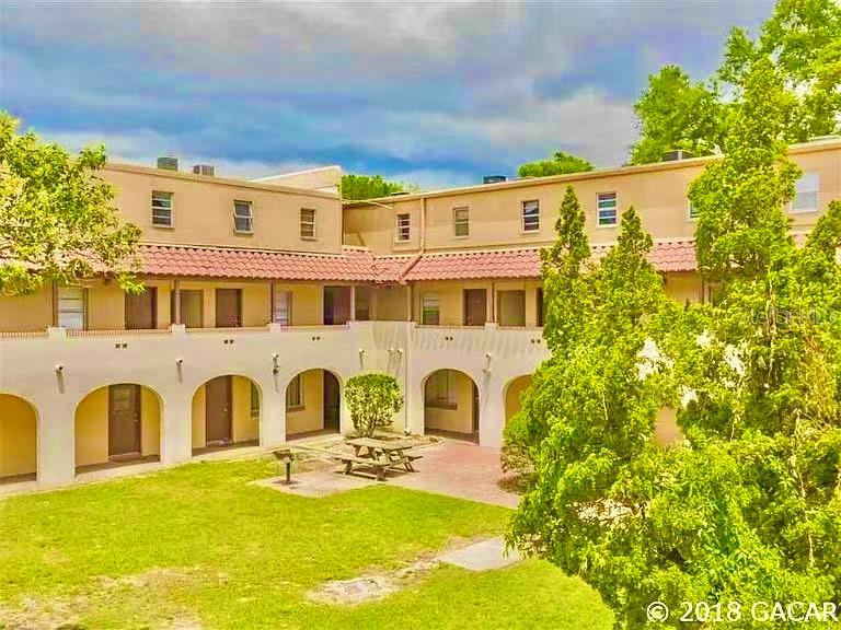 An exterior view of a multi-story apartment building with arched walkways and a central courtyard — 914 SW 8TH AVENUE UNIT 42, GAINESVILLE, FL