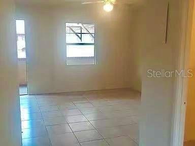 A room with light-colored tile flooring, a ceiling fan, and a window overlooking an exterior area — 914 SW 8TH AVENUE UNIT 42, GAINESVILLE, FL