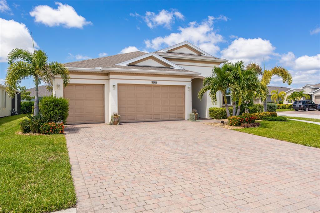 A single-story house with a three-car garage, paved driveway, and palm trees under a blue sky — 3286 BARAVALDO CIRCLE, CAPE CORAL, FL