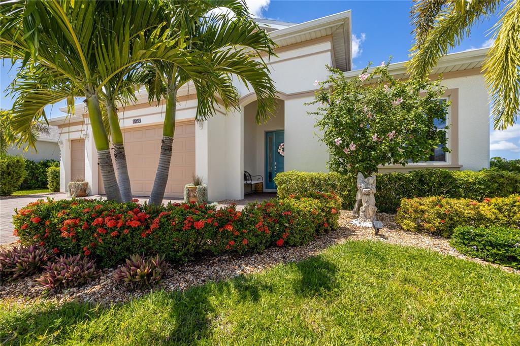A single-story house with a tan garage, blue front door, and landscaped front yard — 3286 BARAVALDO CIRCLE, CAPE CORAL, FL