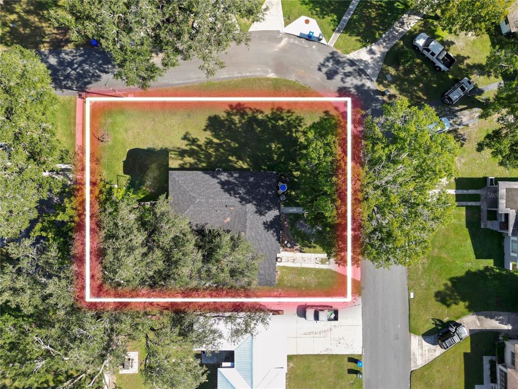 An aerial view shows a house with a dark roof surrounded by trees and grass — 621 HILLSIDE DRIVE, LAKELAND, FL