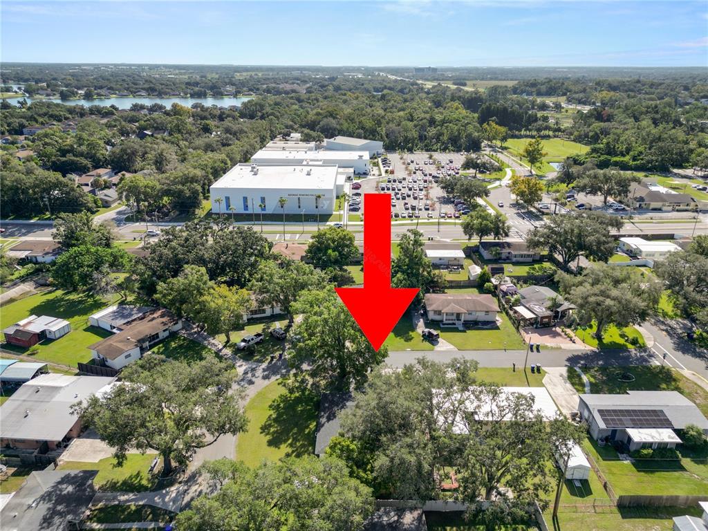 An aerial view shows a residential house surrounded by trees with a red arrow pointing down — 621 HILLSIDE DRIVE, LAKELAND, FL