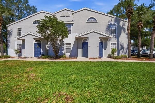 A two-story gray apartment building with blue front doors and a grassy front lawn — 1601 COLUMBIA ARMS CIRCLE UNIT 201, KISSIMMEE, FL