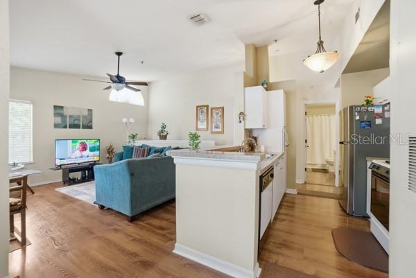 An open-concept living room and kitchen featuring wood-look flooring and a blue sofa — 1601 COLUMBIA ARMS CIRCLE UNIT 201, KISSIMMEE, FL