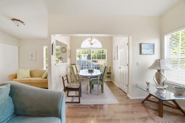 A living room and dining area feature light wood floors, neutral walls, and large windows — 1601 COLUMBIA ARMS CIRCLE UNIT 201, KISSIMMEE, FL